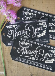 three tags with thank you written on them sitting next to some pink flowers and purple carnations