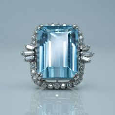 Contemporary 16 Carat Aquamarine and Diamond Ring This magnificent 16 carat rectangular cut mediterranean blue aquamarine is set in a raised woven basket setting of 18ct white gold (marked London/Leopard/1986) with a spray of three baguette cut diamonds to each shoulder. The aquamarine is surrounded by a halo of brilliant cut diamonds measuring approximately .50 carats, G colour and VS Clarity.  The plain shoulders lead to a plain band shank which has had the addition of "beads" to prevent the r Aquamarine Ring Vintage, Blue Aquamarine Ring, Statement Rings Diamond, Mediterranean Blue, Basket Setting, Plain Bands, Etsy Gold Ring, Aquamarine Ring, Baguette Cut Diamond