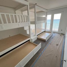 an empty room with white bunk beds and wooden flooring on the side of it