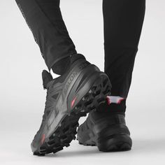 the bottom view of a pair of black and red running shoes on a person's feet