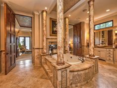 a large bathroom with marble flooring and columns on the walls, along with an oval jacuzzi tub