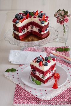 two pieces of red velvet cake with berries and cream on top, one slice missing