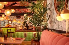 the interior of a restaurant with pink booths and green tiles on the walls, potted plants