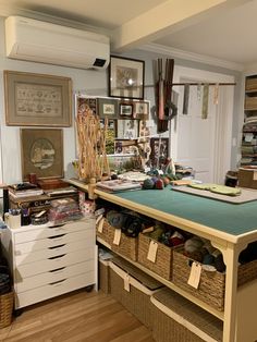 a sewing room with lots of crafting supplies on the table and hanging pictures above it