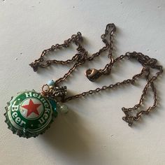 a close up of a bottle cap on a chain with a charm attached to it