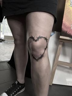 a woman's leg with barbed wire in the shape of a heart on it