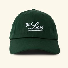 a green hat with the words do less printed in white on it, against a white background