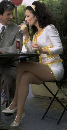 a man and woman sitting at a table with drinks in their hands, talking to each other