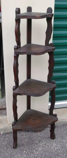 three tiered wooden shelf sitting on the side of a building