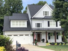 a large white house with black roof and two car garages in the front yard