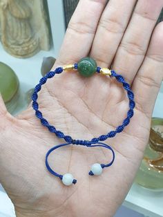 a hand holding a blue string bracelet with two beads