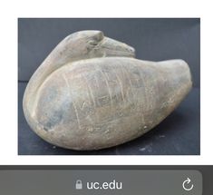 an old clay bird with writing on it's side sitting on a black surface