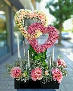 a heart shaped arrangement with candles and flowers