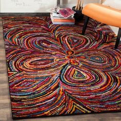 a colorful rug on the floor with a chair in front of it and a plant