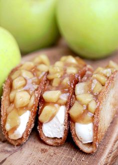 three pieces of food sitting on top of a wooden cutting board next to green apples