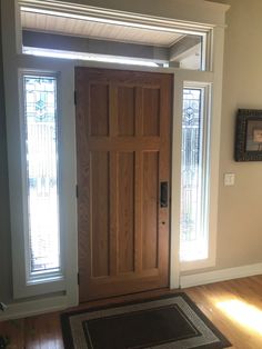 an empty room with a wooden door and rug on the floor next to two windows