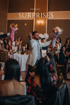 a man standing in front of a group of people at a wedding with flowers and balloons