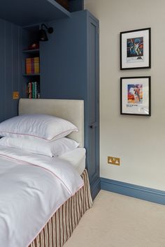 a bed with white pillows and two pictures on the wall next to it in a bedroom