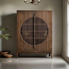 a wooden cabinet sitting in front of a window next to a potted green plant