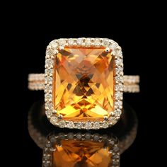 an orange and white diamond ring sitting on top of a black surface with diamonds around it