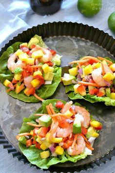 three lettuce cups filled with shrimp and veggies on top of a pan