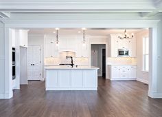 an empty kitchen with white cabinets and wood floors