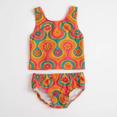 This groovy two piece swimsuit will look so cool on your little girl while she enjoys summer fun in the sun. Featuring a groovy flower and geometric print, this swimsuit is an easy upgrade on her summer wardrobe. The back features faux bows for a cool, unique style. Spring Playful Tankini For Swimming, Summer Beachwear Tankini For Playtime, Summer Beachwear Tankini, Playful Tankini For Beach Party, Summer Beach Tankini For Playwear, Summer Beach Season Tankini For Play, Playful Spring Tankini, Playful Sleeveless Tankini For Beach Party, Summer Tankini For Beachwear