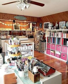 a room filled with lots of crafting supplies on top of a wooden floor next to a ceiling fan