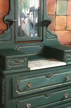 a green dresser with a mirror on it and a brick wall in the back ground