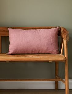 a wooden bench with a pink pillow on it