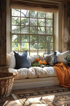 a white couch sitting under a window next to a basket filled with orange and green flowers