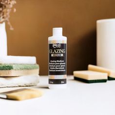 a bottle of glaze sitting on top of a table next to some other items