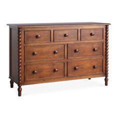 a wooden dresser with many drawers and knobs on the bottom drawer, against a white background