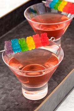 two martini glasses with gummy bears in them on a tray, ready to be served