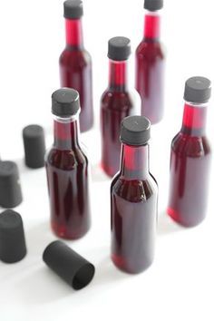 there are many bottles with black caps on the top and one red bottle in the middle