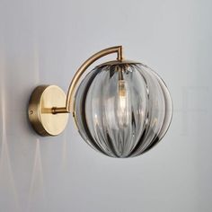 a wall light with a glass ball on it's arm and two lights attached to the side