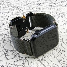 an apple watch sitting on top of a map next to a pair of black buckles