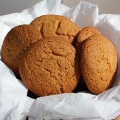 three cookies sitting on top of white paper in a basket next to a wooden spoon