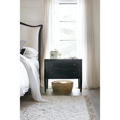 a bedroom with a white bed and black dresser in front of a window that has sheer curtains