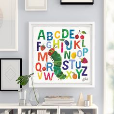 the very hungry caterpillar alphabet art print in white frame on wall above bookshelf