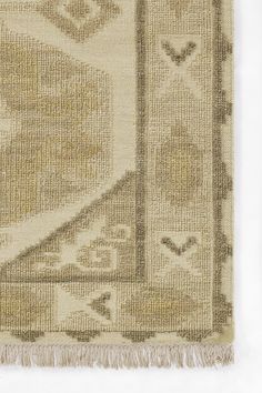 an old rug with fringes on the edges and a design in grey, beige and white