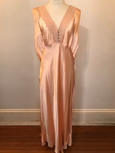 This 1940-50s pink satin taffeta nightgown/slip dress has a lacey v neck with small appliqué flowers at the center.  Bust: 50" Waist: 44" Hip: 46" Length: 48" Vintage V-neck Evening Slip Dress, Vintage V-neck Wedding Sleepwear, V-neck Bias Cut Wedding Nightgown, V-neck Bias Cut Nightgown For Wedding, V-neck Wedding Nightgown With Bias Cut, Pink Satin V-neck Nightgown, Vintage V-neck Wedding Nightgown, Vintage Satin Wedding Sleepwear, Vintage Satin Sleepwear For Wedding