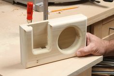 a person is holding a wooden object with holes in the front and back, on top of a workbench