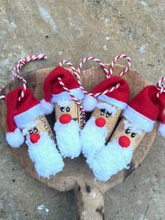 three christmas decorations on top of a piece of wood with candy canes in the shape of santa's faces