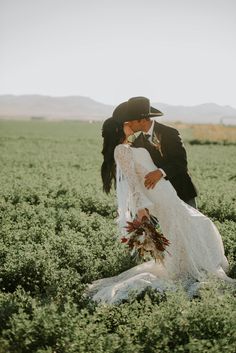 a bride and groom kissing in a field