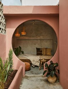 a bed sitting in the middle of a pink wall next to a potted plant