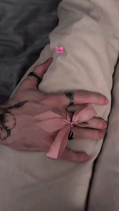 a woman's hand with two rings on it and a pink bow tied around her wrist