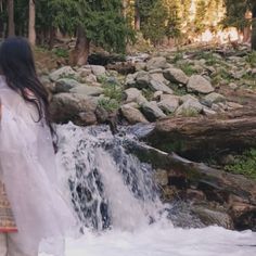 a woman standing in front of a waterfall