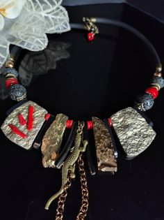 Beautiful modern style choker necklace with an ethnic touch. The necklace is made of large irregular flakes of agate and bone stone galvanized in gold, lava stone, red coral and hematite. The central part of the necklace is made with rather large stones which make the necklace very eye-catching. This necklace is the fruit of my imagination, it is an artistic jewel created with various natural stones and crystals. The necklace is rigid but rests naturally on the neck, very comfortable to wear. The back is made with silicone cord. The necklace is very bright, 47cm long with an adjustable hook clasp. The necklace is in shades of gold, black, and red which make it very elegant. It is a particular necklace, for those who love handmade pieces. The necklace is very elegant, very beautiful in summ Gold Necklace With Natural Stones For Festivals, Unique Red Coral Jewelry With Natural Stones, Unique Choker Necklace With Natural Stones, Gold Metal Jewelry With Gemstone Beads, Gold Beaded Choker With Natural Stones, Bohemian Gold Choker With Natural Stones, Unique Metal Necklace With Natural Stones, Adjustable Metal Necklace With Gemstone Beads, Traditional Gold Necklaces With Red Coral