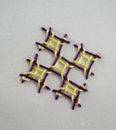 an image of some kind of stitching on a white tablecloth with purple and yellow squares